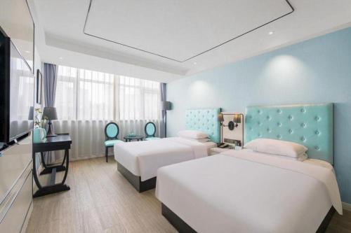 青島市にあるQingdao Galaxy Holiday Hotelのベッド2台とテレビがあるホテルの部屋