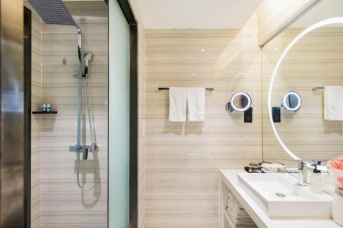 a bathroom with a shower and a sink and a mirror at Xana Hotelle· Tianjin Railway Station Jinwan Square Binjiang Avenue in Tianjin
