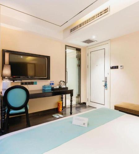 a room with a bed and a tv and a chair at Xana Hotelle· Tianjin Railway Station Jinwan Square Binjiang Avenue in Tianjin
