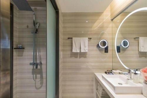 a bathroom with a shower and a sink and a mirror at Xana Hotelle· Tianjin Railway Station Jinwan Square Binjiang Avenue in Tianjin