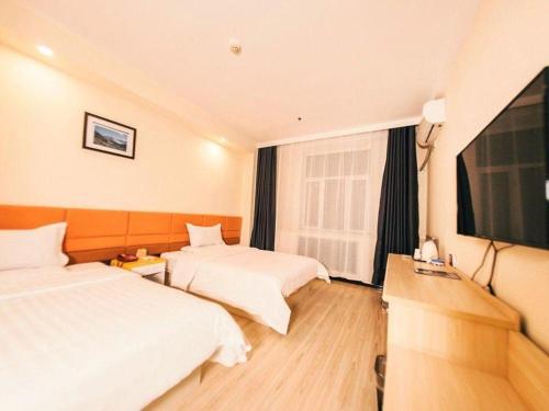 a hotel room with two beds and a flat screen tv at 7 Days Inn Harbin Medical University First Affiliated Hospital in Harbin