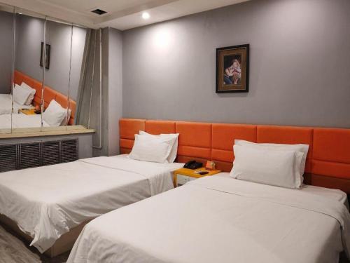 a hotel room with two beds and a mirror at 7 Days Inn Harbin Medical University First Affiliated Hospital in Harbin