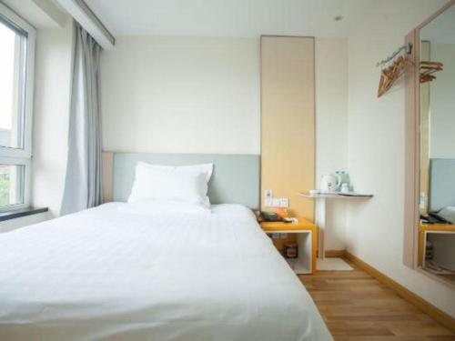 a bedroom with a large white bed and a window at 7 Days Inn Harbin West Railway Station in Harbin