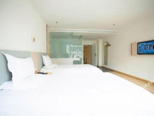 a bedroom with a large white bed and a tv at 7 Days Inn Harbin West Railway Station in Harbin