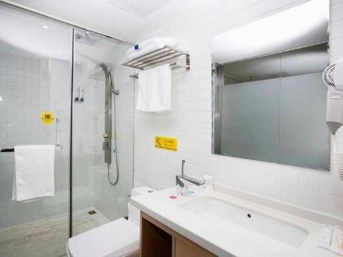 a bathroom with a shower and a sink and a mirror at 7 Days Inn Harbin West Railway Station in Harbin