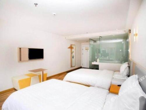 a hotel room with two beds and a television at 7 Days Inn Harbin West Railway Station in Harbin