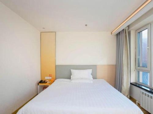 a bedroom with a large white bed and a window at 7 Days Inn Harbin West Railway Station in Harbin