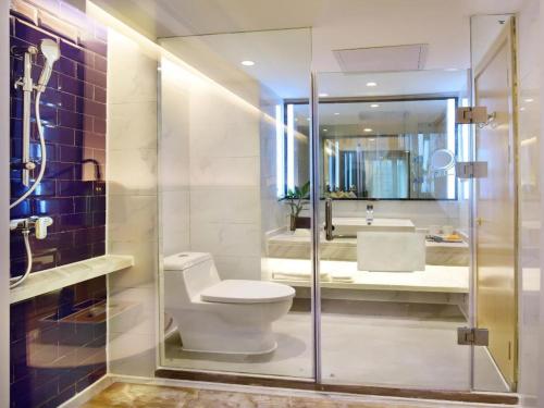 a bathroom with a toilet and a shower and a sink at Kyriad Marvelous Hotel Yiyang Xiufeng Park in Yiyang