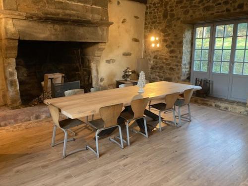 une table et des chaises en bois dans une pièce avec une cheminée dans l'établissement Manoir 15 mn des plages, à Hénansal