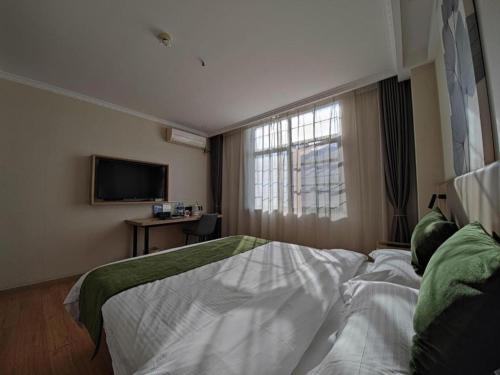 a bedroom with a bed and a tv and a window at GreenTree Inn Xuzhou High Speed Railway Station Express Hotel in Xuzhou