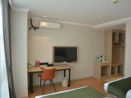 a room with a desk with a television and a chair at GreenTree Inn Xuzhou High Speed Railway Station Express Hotel in Xuzhou