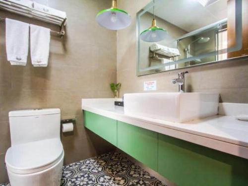 a bathroom with a sink and a toilet and a mirror at GEM Hotel Ningbo Tongtu Road Minglou Metro Station in Ningbo