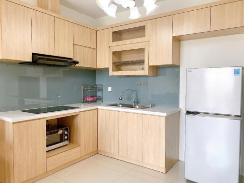 a kitchen with wooden cabinets and a white refrigerator at The Sun Avenue Serviced Apartment in Ho Chi Minh City