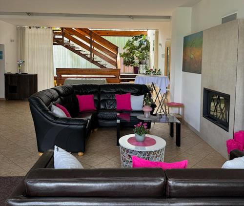 a living room with a leather couch and pink pillows at Penzion Kozí Horka u Brněnské přehrady in Brno