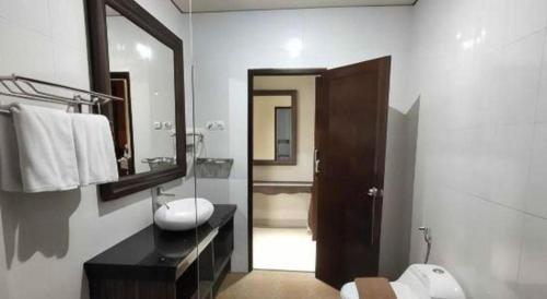 a bathroom with a sink and a toilet and a mirror at Fafa Hill Hotel and Resort in Bogor