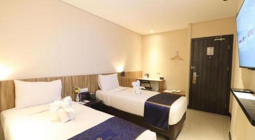 a hotel room with two beds and a flat screen tv at Fitra Hotel Majalengka in Majalengka