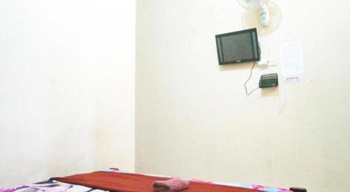 a room with a bed and a tv on a wall at Penginapan Arsyana in Pacitan