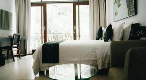 a bedroom with a bed and a couch and a glass table at VillaTel Salse in Bandung