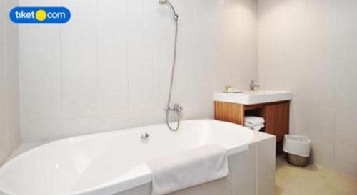 a white bathroom with a tub and a sink at Kenari Tower Hotel in Makassar