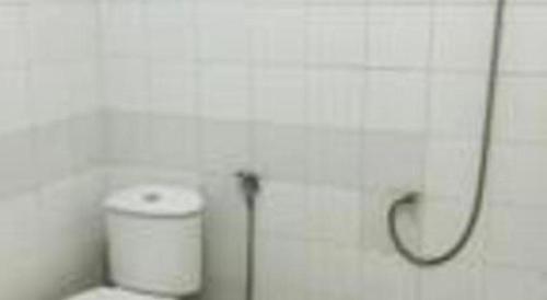 a bathroom with a toilet with a hose on the wall at Hotel Huswah Airport in Jakarta