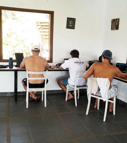 a group of three men sitting at a desk at Merdeka House in Maluk