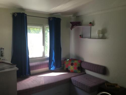 a room with a window with blue curtains and a bench at Mobil home PAPILLON in La Celle-sous-Gouzon