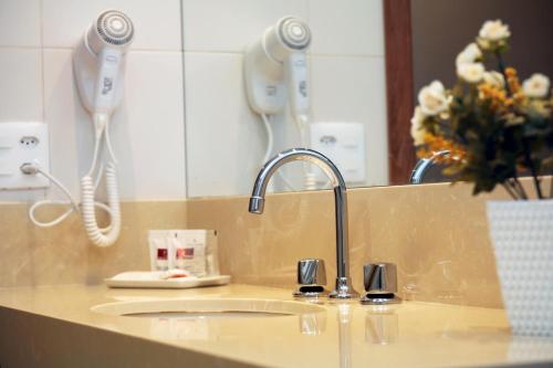 um balcão de casa de banho com um lavatório e um espelho em Mengo Palace Hotel no Rio de Janeiro
