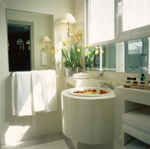 La salle de bains blanche est pourvue d'un lavabo et d'un miroir. dans l'établissement Casa Corp Boutique Suites in Condesa, à Mexico