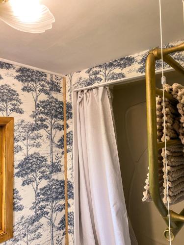 a bedroom with blue and white wallpaper and a curtain at The Meadow Snug in Baschurch