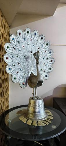 a metal peacock statue sitting on a glass table at Banarasi Courtyard in Varanasi