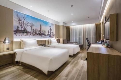 two beds in a hotel room with a painting on the wall at Atour Hotel Weihai Shidao in Dongshan