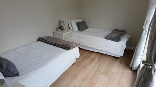 two beds in a room with wooden floors at Lily Lane in Gqeberha