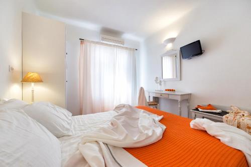 a bedroom with a white bed with an orange blanket at Yades - All Sea VIew Suites - Adults only in Naousa