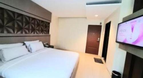 a bedroom with a bed and a flat screen tv at Alexander Hotel Tegal in Tegal