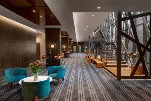 a lobby with a staircase and blue chairs at Hyatt Centric Las Condes Santiago in Santiago