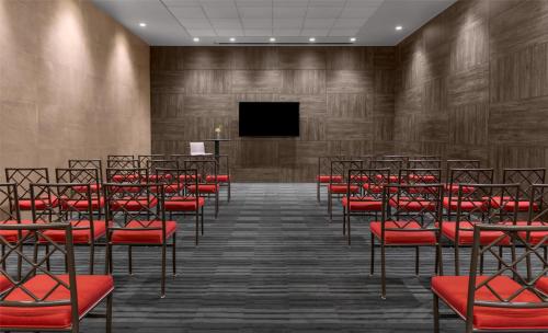 an empty lecture room with red chairs and a screen at Hyatt Centric Las Condes Santiago in Santiago