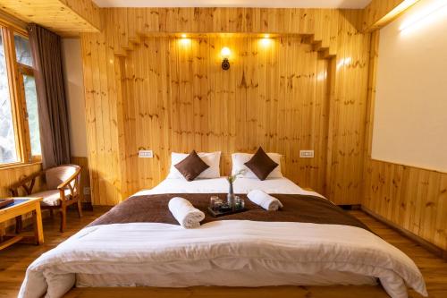 a large bed in a room with wooden walls at The Evara Stays, Jibhi in Jibhi