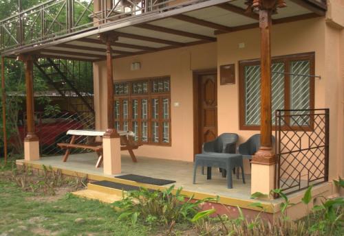 a house with a porch with chairs and a table at Tamarind Tree Masinagudi in Masinagudi
