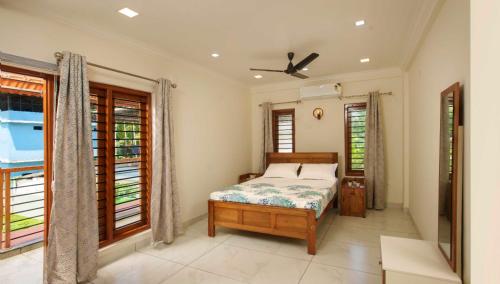ein Schlafzimmer mit einem Bett und einigen Fenstern in der Unterkunft Matts Homestay Alleppey in Jāmb