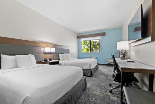 a hotel room with two beds and a desk at La Quinta Inn & Suites by Wyndham Santa Cruz in Santa Cruz