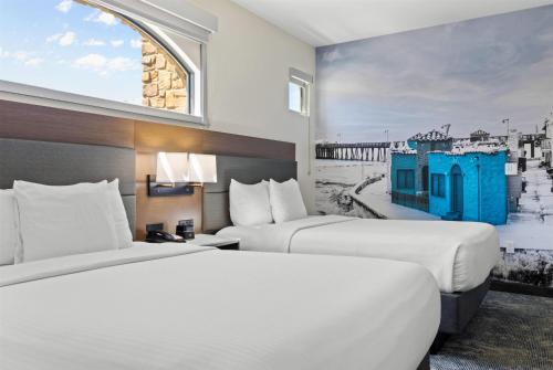 two beds in a hotel room with a painting on the wall at La Quinta Inn & Suites by Wyndham Santa Cruz in Santa Cruz