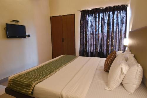 a bedroom with a bed with a television and a window at The Byke Old Anchor Beach Resort & Spa in Cavelossim