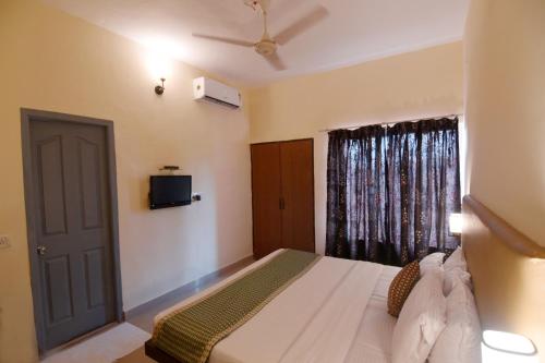 a bedroom with a bed with a television and a window at The Byke Old Anchor Beach Resort & Spa in Cavelossim