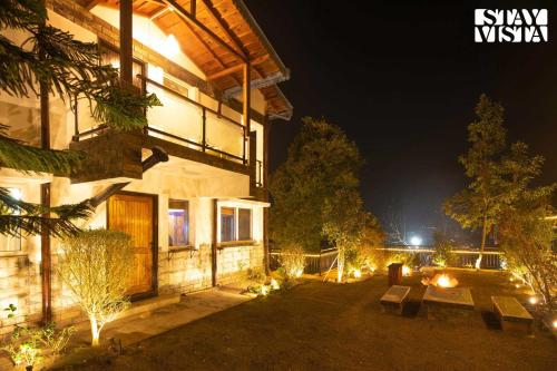 a building with benches and lights at night at StayVista at Viva La Vida - Bonfire, Jacuzzi, AC in Bhīm Tāl