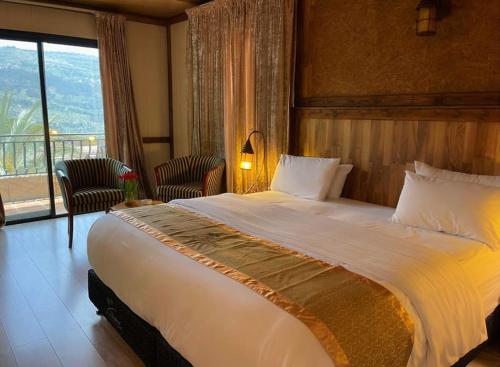 a large bed in a hotel room with a balcony at Pineland Hotel and Health Resort in Ḩammānā
