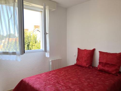 - une chambre avec un lit doté de draps rouges et une fenêtre dans l'établissement Au gré du vent - Saint Gilles Croix de Vie, à Saint-Gilles-Croix-de-Vie