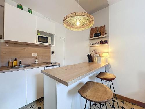 une cuisine avec des armoires blanches et un comptoir avec des tabourets dans l'établissement Le BEHNA - Wi-Fi Apartment - Air Conditioning, à Narbonne
