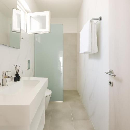 a white bathroom with a sink and a toilet at Le Sands in Kos Town