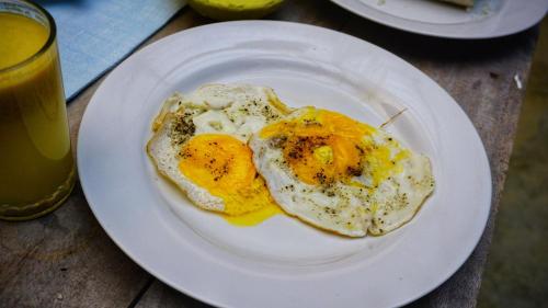 two fried eggs on a white plate on a table at Jungle Edge Home Sigiriya in Sigiriya