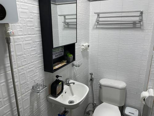 a white bathroom with a toilet and a sink at Goldland Caelestis Guest House in Bacolod